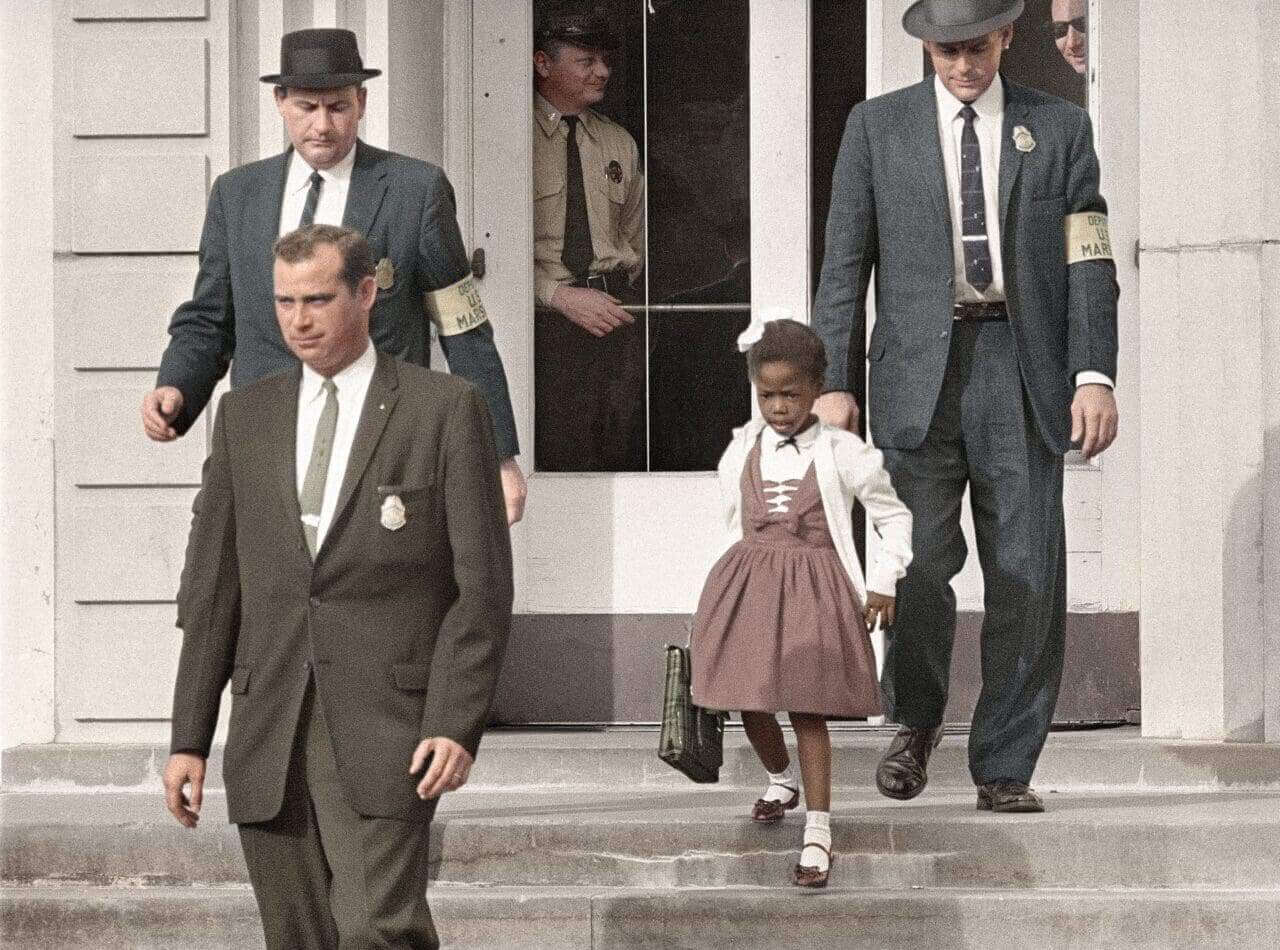 img 4670 Ruby bridges as a child walking down the steps of a school with three white men around her.