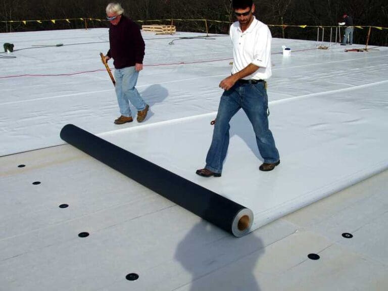 Workers lay down white pvc roofing material